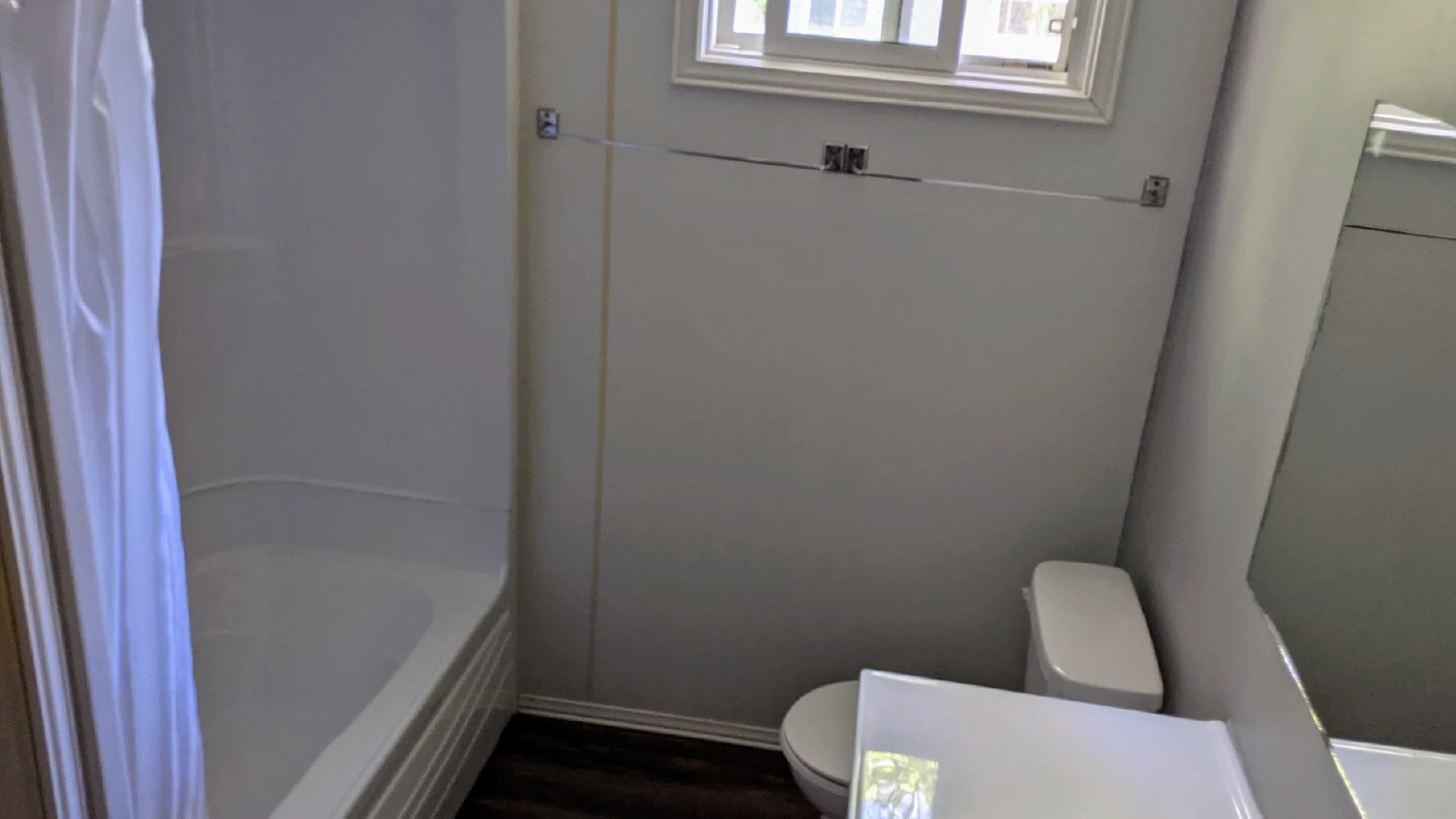 Pigeon Lake Resort Cottage three bathroom with bathtub, shower curtain, toilet, and mirror.